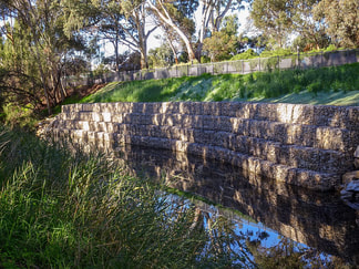 two level retaining wall surrounded by greenery and water