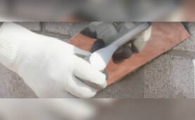 gloved hand of a masonry contractor smoothing down concrete block wall