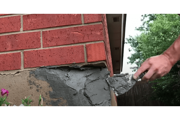 masonry contractor doing some parging work on the side of a brick building
